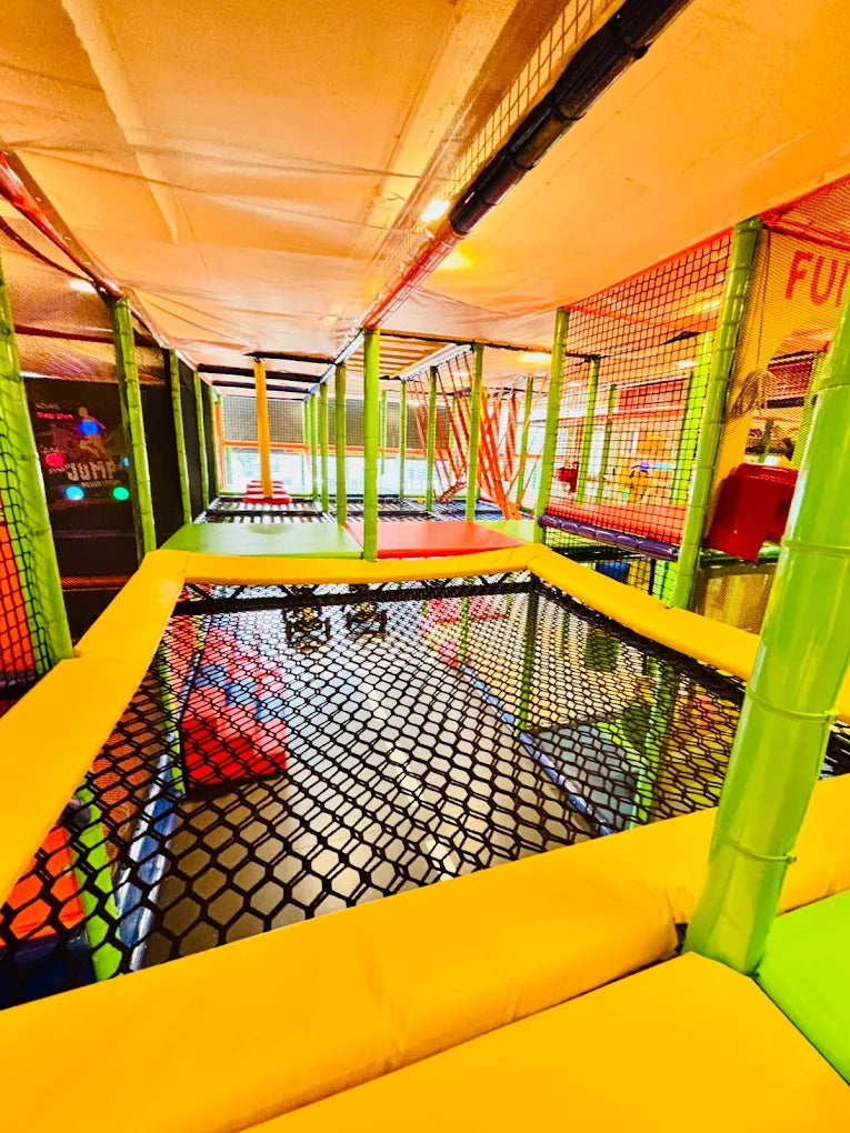 A colorful indoor playground with trampolines and soft play areas for children.
