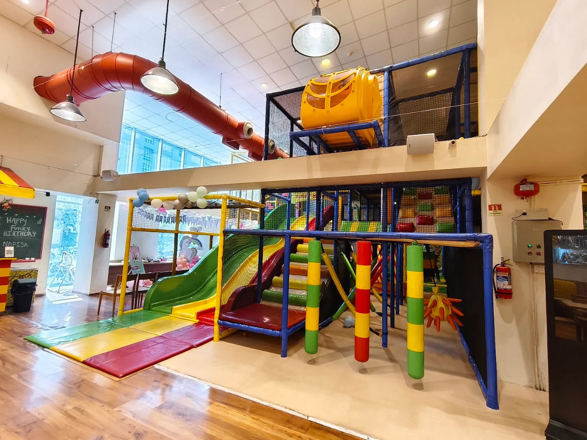 A colorful indoor playground with slides, climbing structures, and soft mats for children.