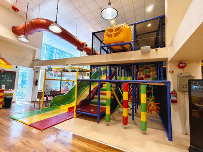 A colorful indoor playground with slides, climbing structures, and soft mats for children.