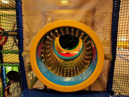 A child plays inside a colorful indoor playground tube.
