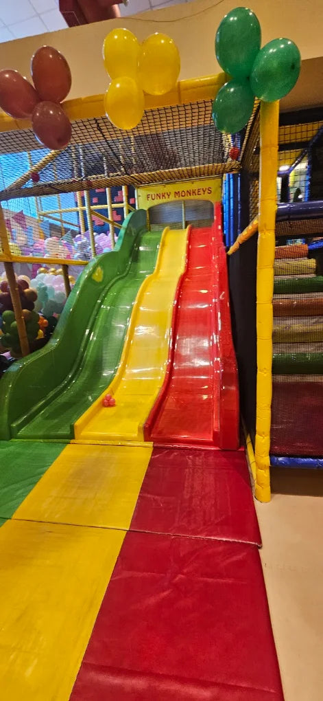 A colorful indoor playground with slides and balloons, likely for young children.