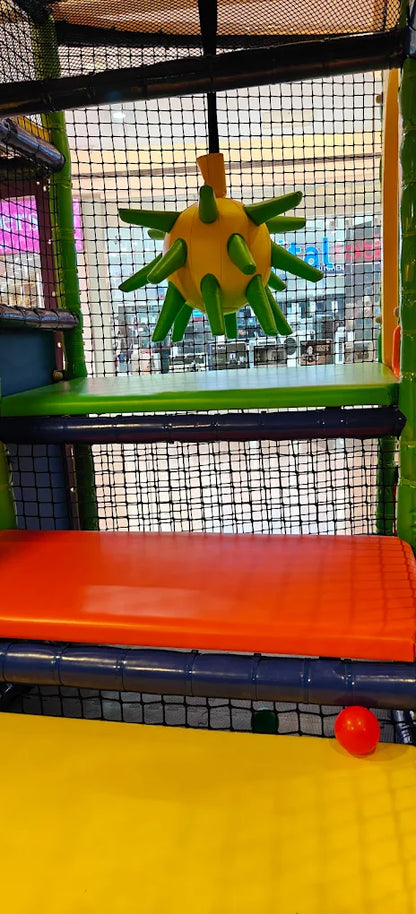 A colorful indoor playground with a spiky yellow and green toy hanging above an orange bench.