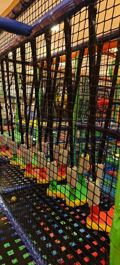 A colorful indoor playground with nets and climbing structures for children.