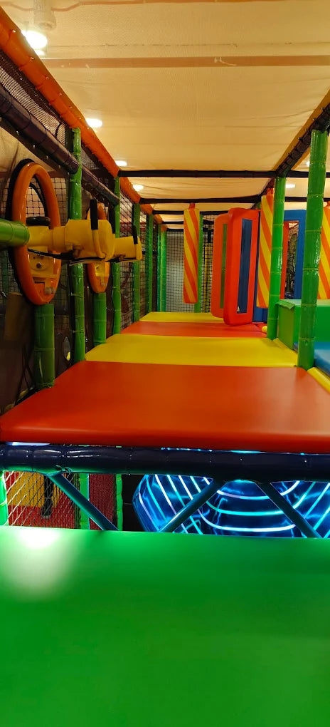 A colorful indoor playground with soft play structures and bright lighting.
