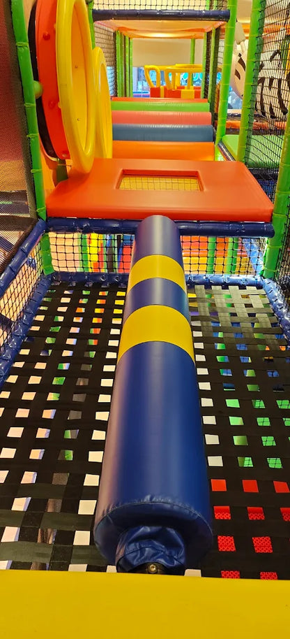 A colorful indoor playground with a blue and yellow padded obstacle for children.