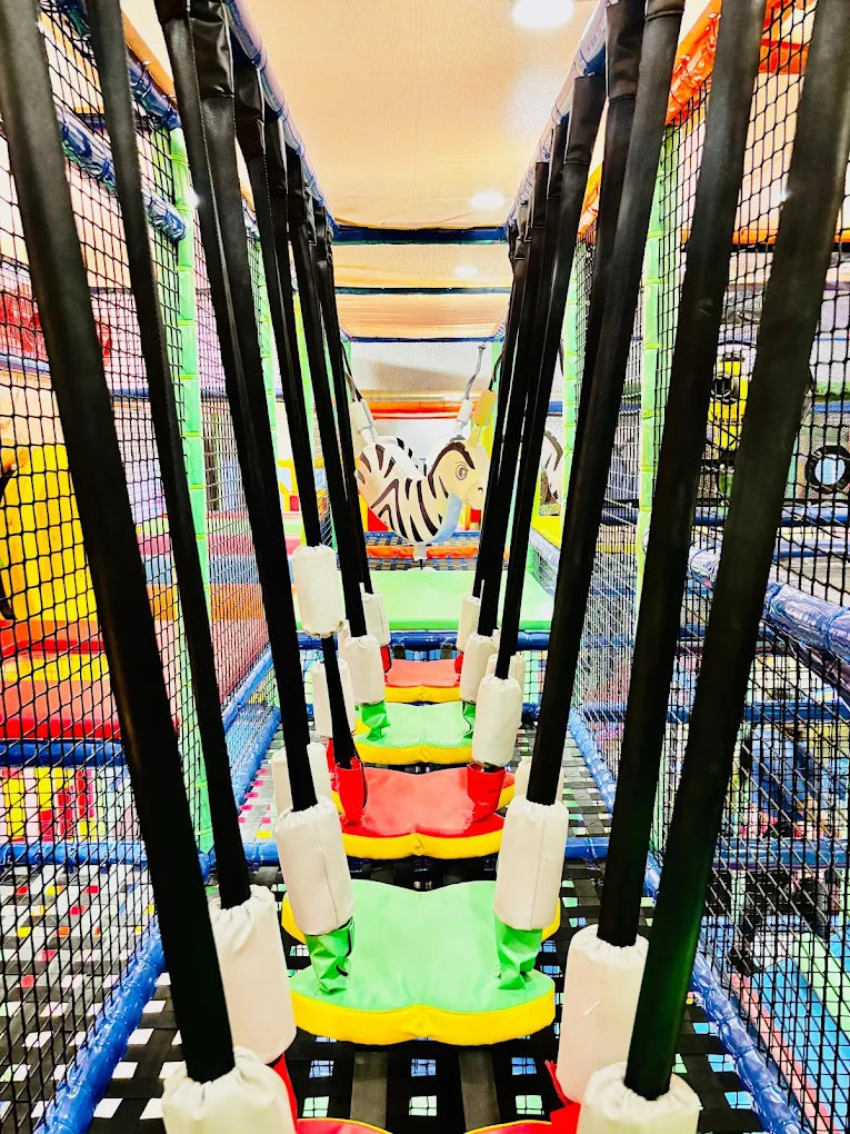 A colorful indoor playground with a rope bridge and a zebra swing.