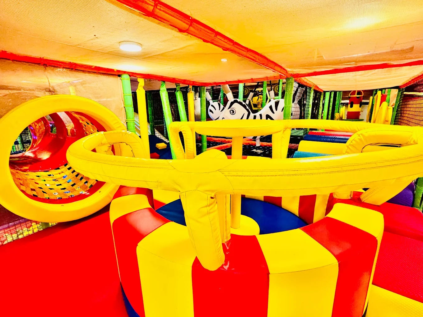A vibrant indoor playground with soft, colorful structures and a tunnel, designed for children's play.