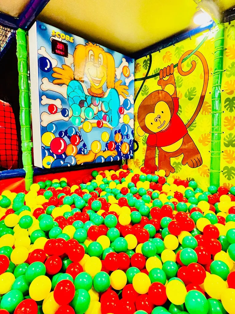 A ball pit filled with red, yellow, and green balls, featuring cartoon characters on the walls.
