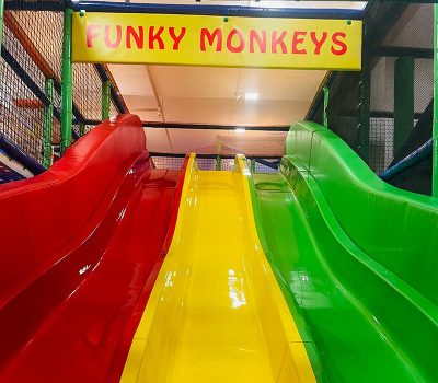Three colorful slides (red, yellow, green) at a children's play area called "Funky Monkeys."