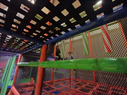 Children play in a colorful indoor playground with nets and tubes.