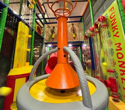 A colorful indoor playground with tubes and a trampoline, likely for children.