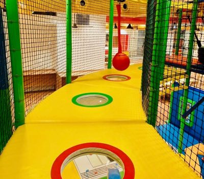 A colorful indoor playground with a red ball hanging and yellow platforms with holes.