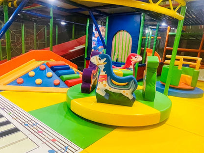 A colorful indoor playground with soft play structures and a rocking horse for young children.
