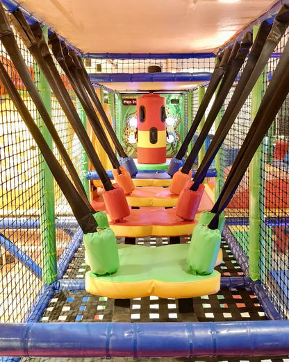 A colorful indoor playground with soft obstacles and swings for children.