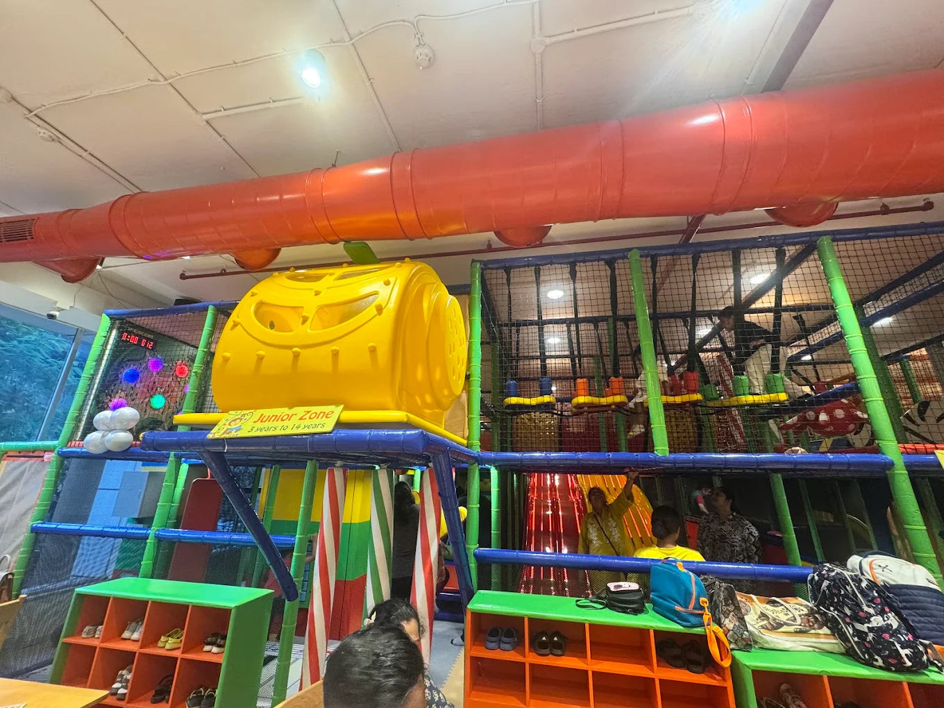 Children play in a colorful indoor playground with slides and climbing structures.