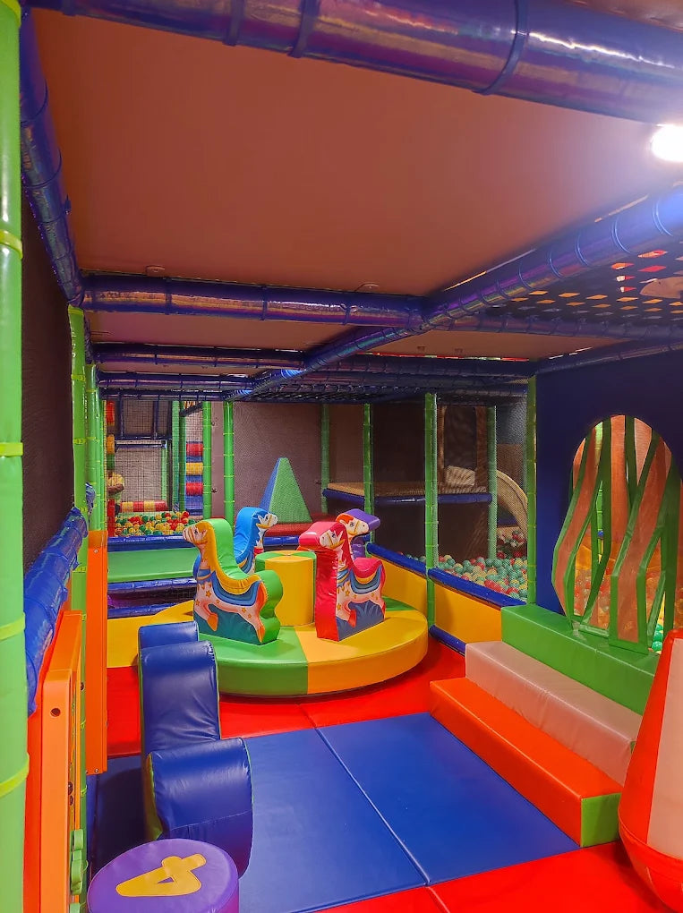 A colorful indoor playground with soft play structures and a ball pit for young children.