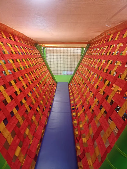 A colorful, netted tunnel in a children's play area with a blue slide.