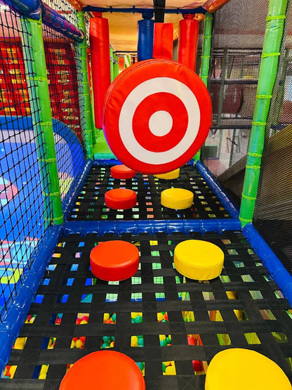 A colorful indoor playground with a target game and soft obstacles for children.