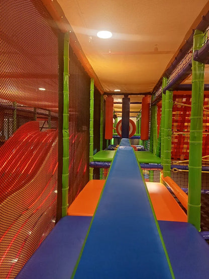 Indoor playground with colorful slides and climbing structures for children.