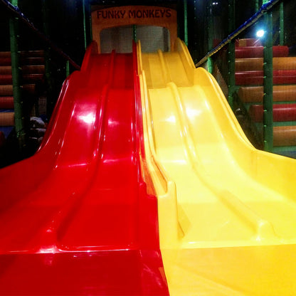 Two bright red and yellow slides at a children's play area, with "FUNKY MONKEYS" signage above.