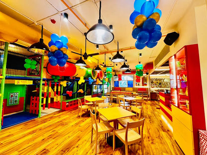 A colorful indoor playground with balloons and tables for toddlers.