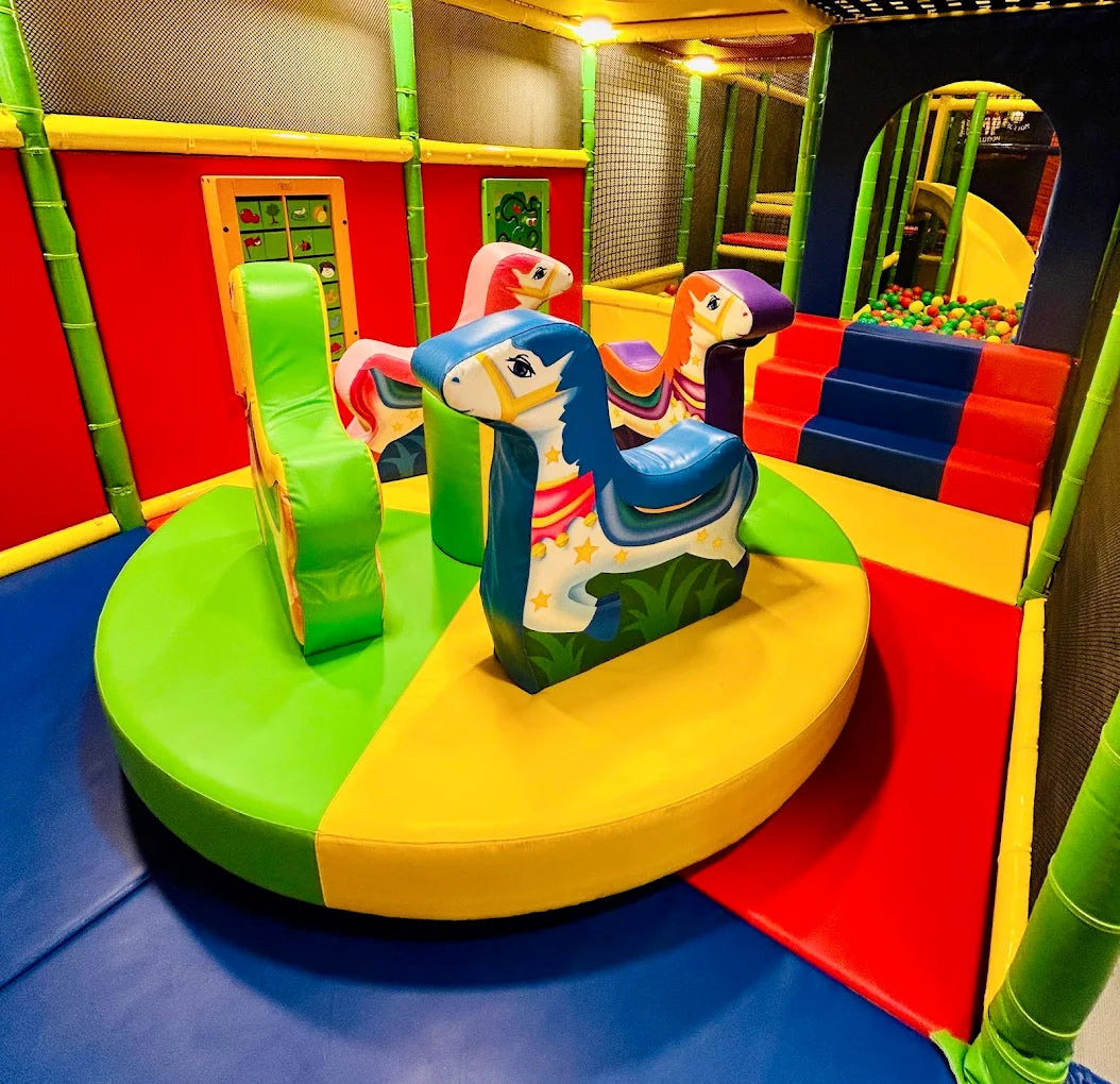 A colorful indoor playground with soft play horses and a ball pit.
