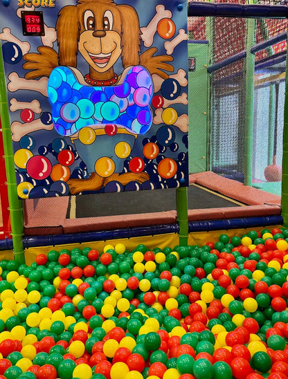 A ball pit filled with colorful balls, with a cartoon dog game in the background.