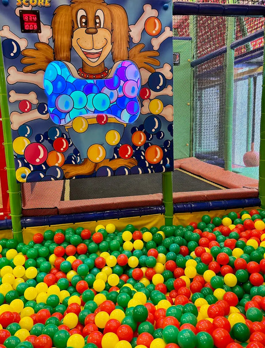 A ball pit filled with colorful balls, with a cartoon dog game in the background.
