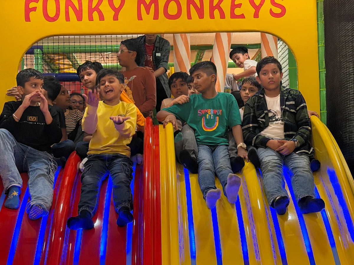 Children on a colorful slide at an indoor playground.