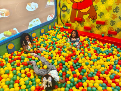 Children play in a ball pit with colorful balls.