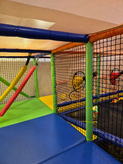 A colorful indoor playground with soft mats and netting.