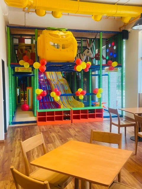 A colorful indoor playground with slides and ball pits, featuring a play structure for young children.