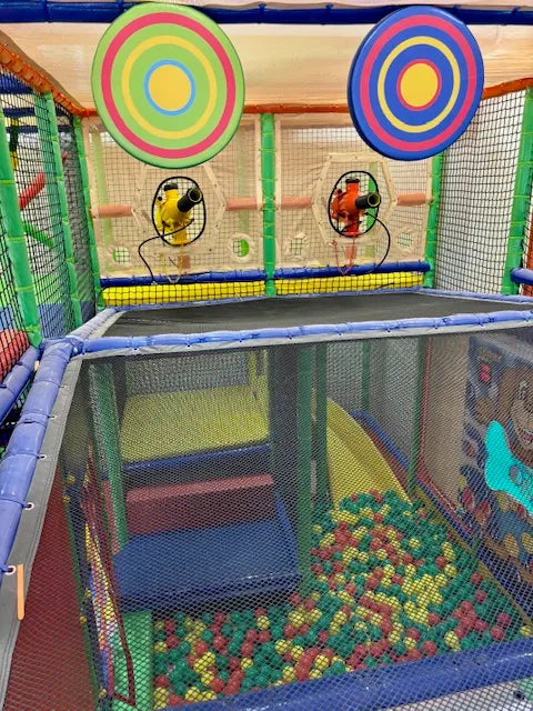 Indoor playground with ball pit, slides, and target games for children.