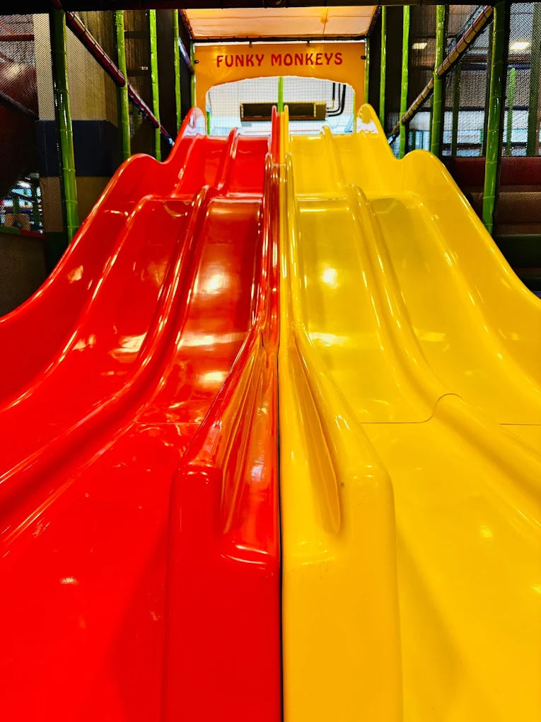 Two bright red and yellow slides in a children's play area.