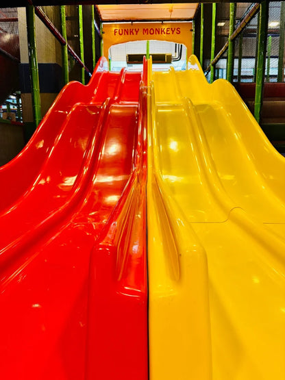 Two bright red and yellow slides in a children's play area.