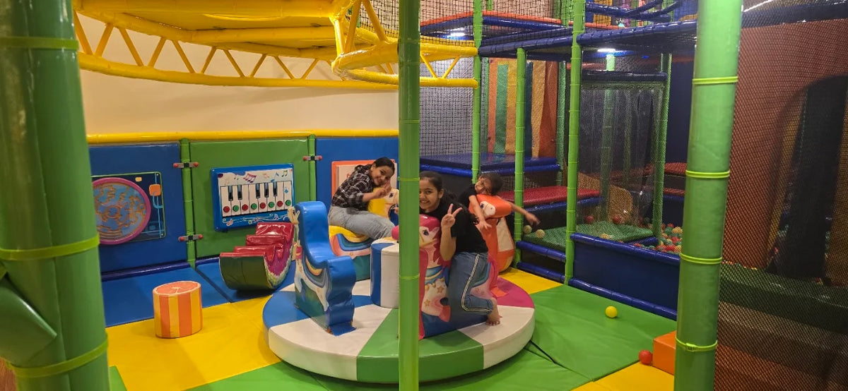 Children play on a carousel in a colorful indoor playground.