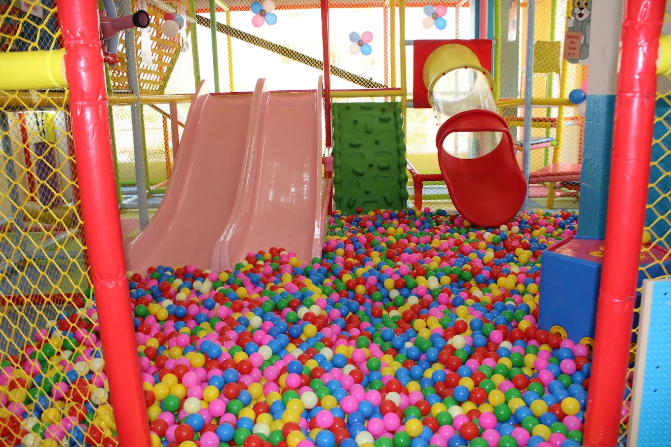 A colorful ball pit filled with children's toys and slides in a play area.