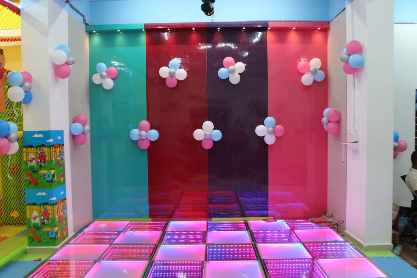 A brightly lit party room with colorful balloons and a light-up dance floor.
