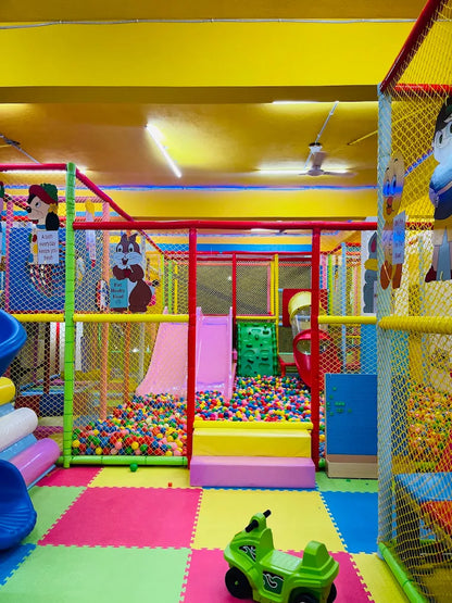 A colorful indoor playground with ball pits, slides, and a toy ATV for children.