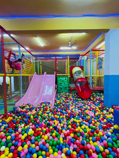 A colorful ball pit with slides and climbing structures in a children's indoor play area.
