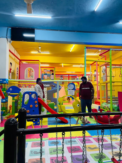A colorful indoor playground with children playing and adults supervising.