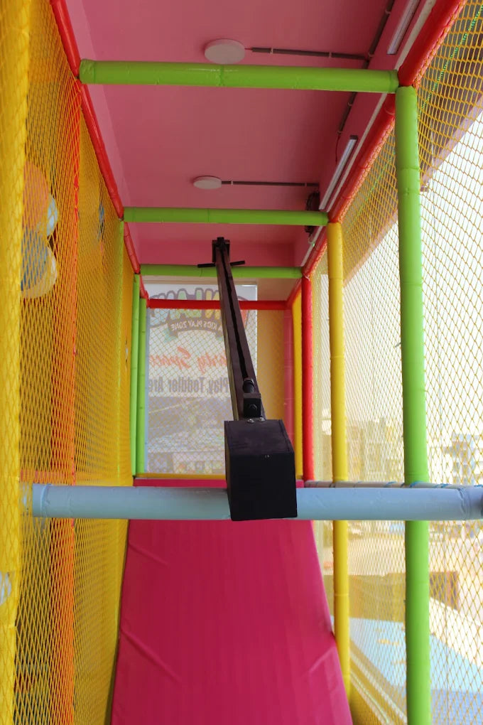 A colorful indoor playground with a zipline apparatus.