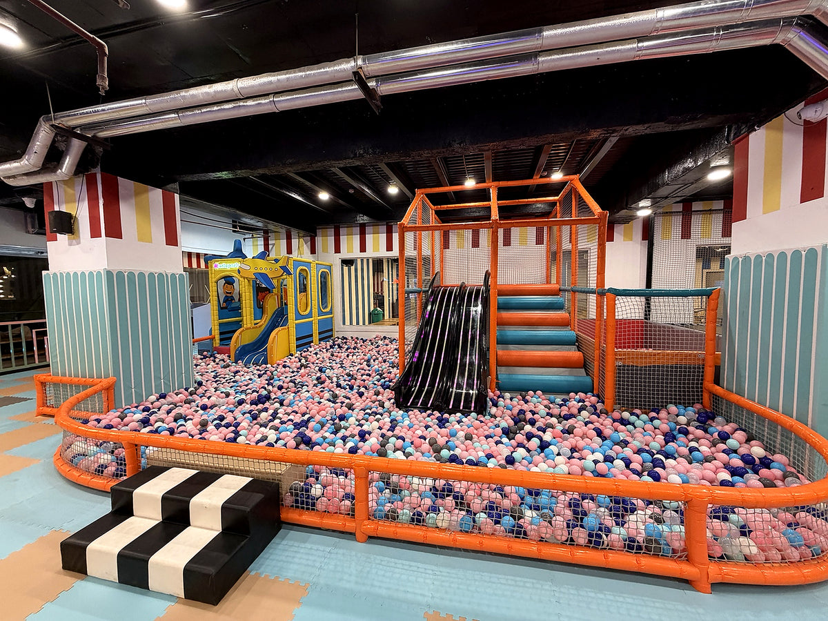 A colorful indoor playground with a ball pit, slide, and climbing structure for children.