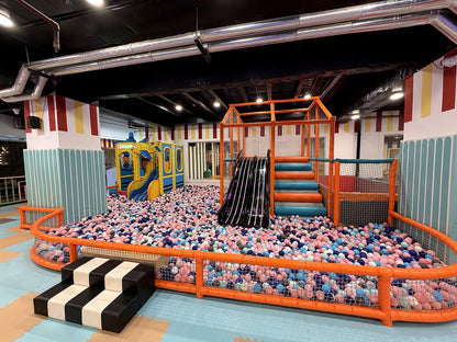 A colorful indoor playground with a ball pit, slide, and climbing structure for children.