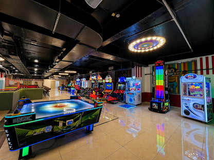 An arcade with various games, including an air hockey table and racing simulators, is brightly lit.