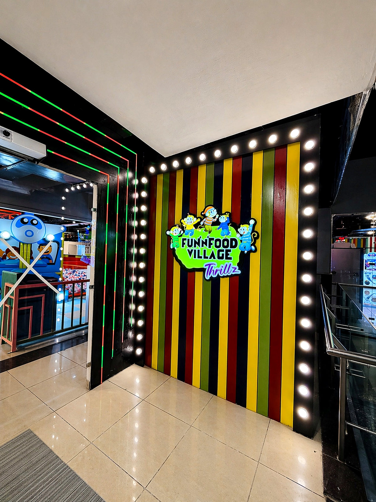 A colorful entrance to "Fun Food Village Thrillz" with cartoon characters and bright lights.