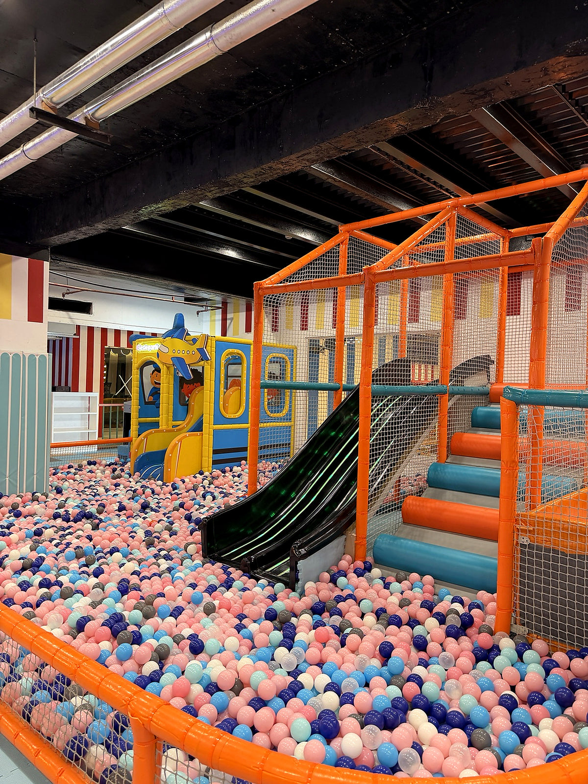 A colorful indoor playground with a ball pit, slides, and climbing structures for children.