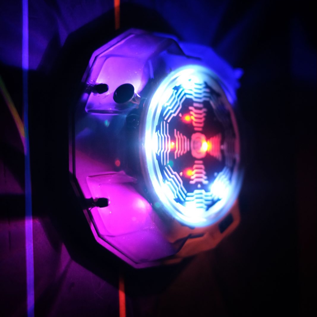 A close-up of a disco ball with colorful lights, casting purple and blue hues.