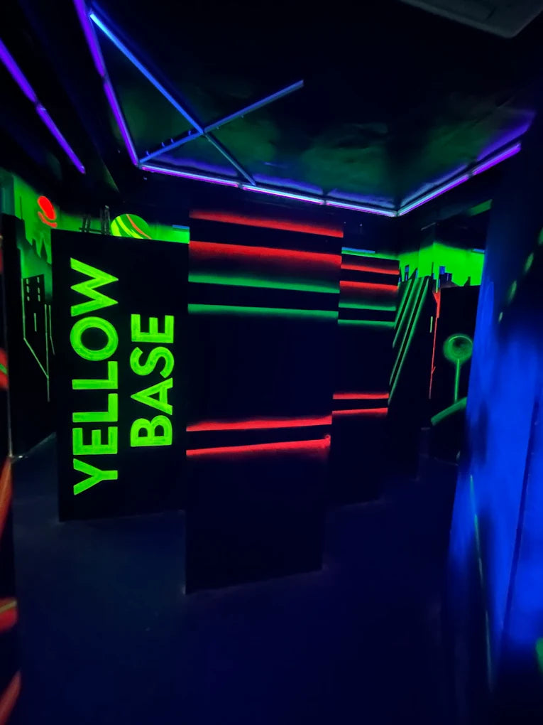 A laser tag arena with neon lights and "YELLOW BASE" signage.