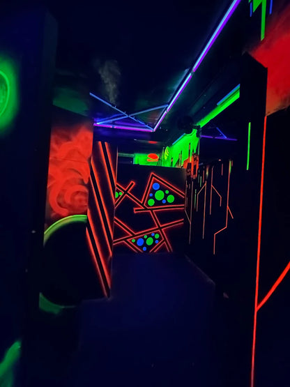A dark laser tag arena with neon lights and geometric patterns.